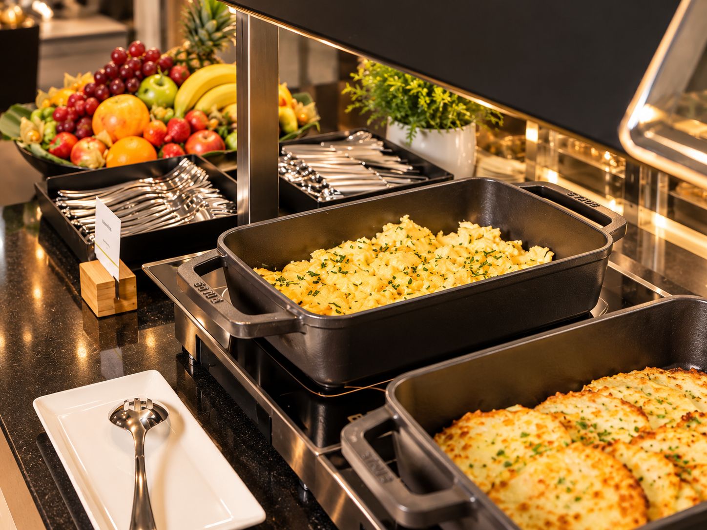 Una barra de buffet con distintos alimentos y utensilios.
