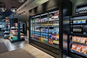 A refrigerated display case stocked with various beverages and snacks in a store. - Doubletree by Hilton Vienna Schonbrunn (Vienna)