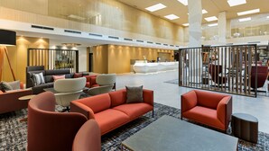 A spacious lobby with modern furniture, a reception desk, and a high ceiling with skylights. - Doubletree by Hilton Vienna Schonbrunn (Vienna)