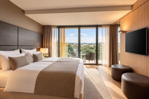 A hotel room with a large bed, a flat-screen TV, a balcony with a view, and a seating area. - Grand Hotel Palace Schönbrunn (Vienna)