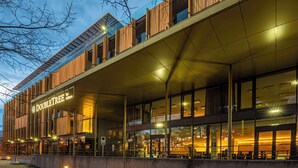 A modern hotel exterior with a prominent "DOUBLETREE by Hilton" sign, large glass windows, and a covered outdoor seating area. - Doubletree by Hilton Vienna Schonbrunn (Vienna)