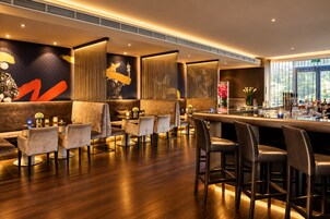 Espaço de bar com assentos, balcão e vista para o exterior.