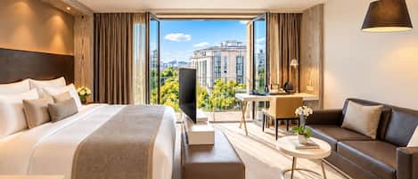 Ein modernes Hotelzimmer mit einem großen Bett, einer Couch, einem Schreibtisch und einem Fernseher.