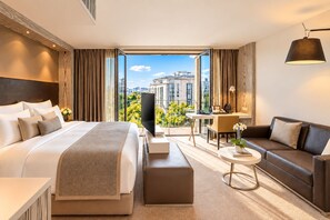 Ein modernes Hotelzimmer mit einem großen Bett, einer Couch, einem Schreibtisch und einem Fernseher.