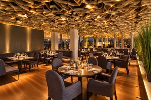 A restaurant with a geometric ceiling design, multiple dining tables, and chairs. - Grand Hotel Palace Schönbrunn (Vienna)