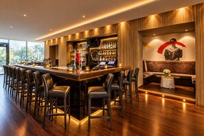 A bar area with a long counter, multiple stools, and a bar stocked with bottles. - Grand Hotel Palace Schönbrunn (Vienna)