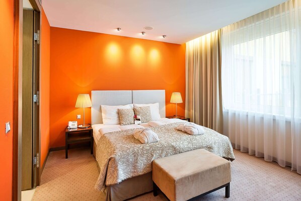 A hotel room with a large bed, two bedside lamps, a bedside table, and a window with sheer curtains. - Austria Trend Hotel Savoyen Vienna (Vienna)