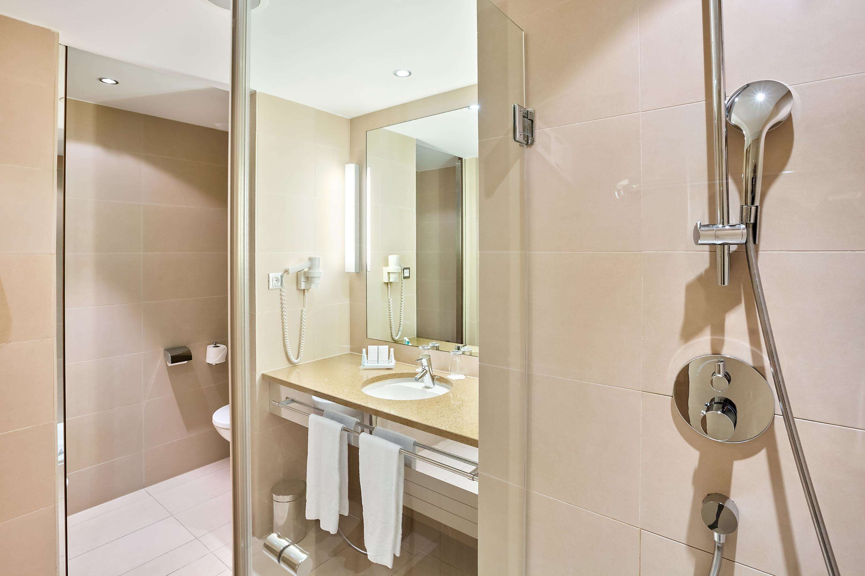 Un baño moderno con cabina de ducha de vidrio, un lavabo con espejo y un perchero para toallas.