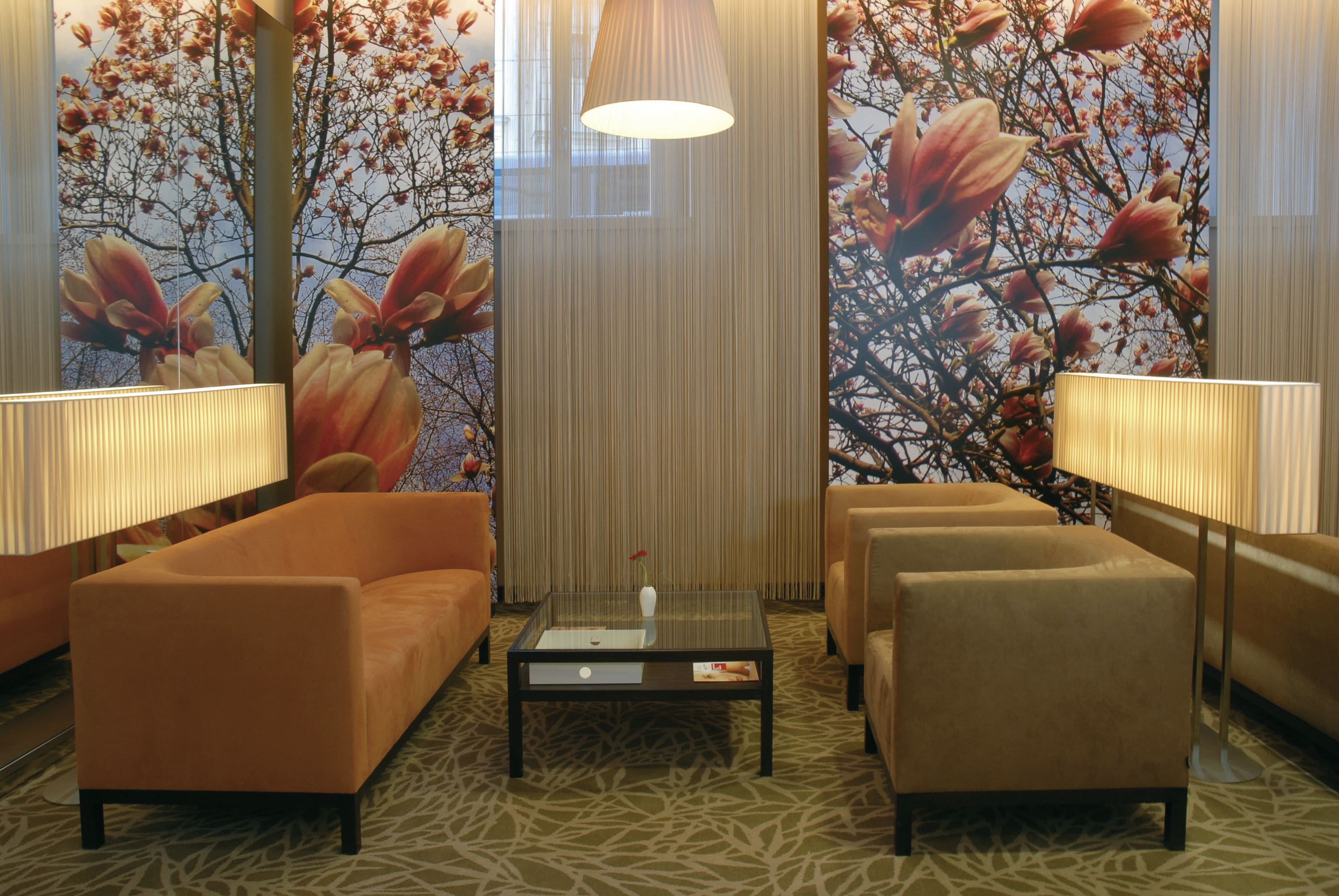 Een moderne zithoek met een glazen salontafel, twee banken en twee vloerlampen.