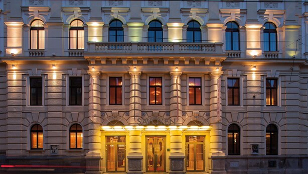 A grand hotel facade with large columns, arched windows, and a well-lit entrance.