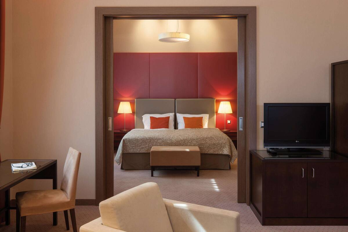 Een hotelkamer met een bed, bedlampen, een televisie, een bureau en een stoel.