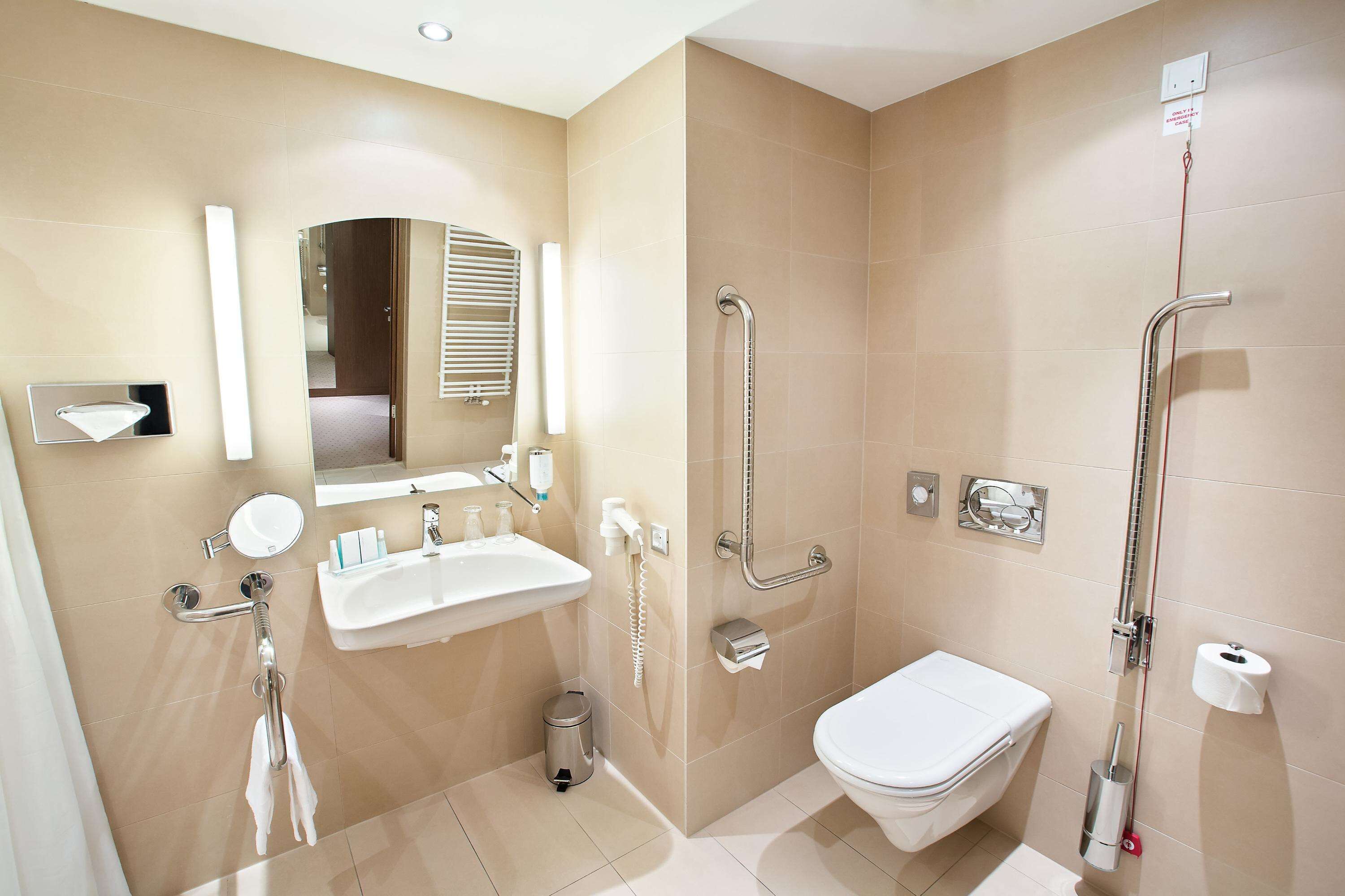 A modern bathroom with a sink, mirror, toilet, and shower.