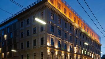 A multi-story building with a classical architectural style, featuring a prominent balcony on the second floor and a series of evenly spaced windows.