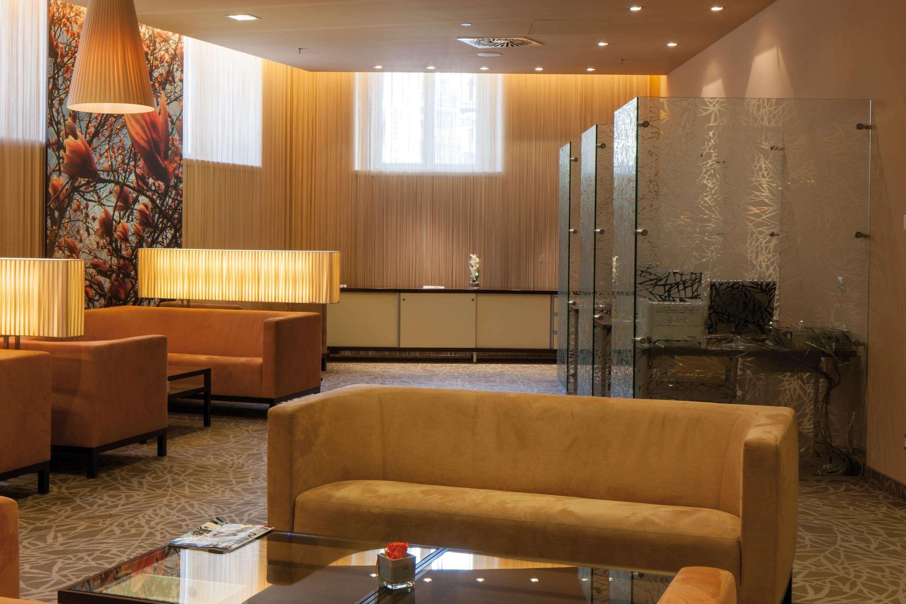 A hotel lobby with seating, a reception desk, and a decorative wall.