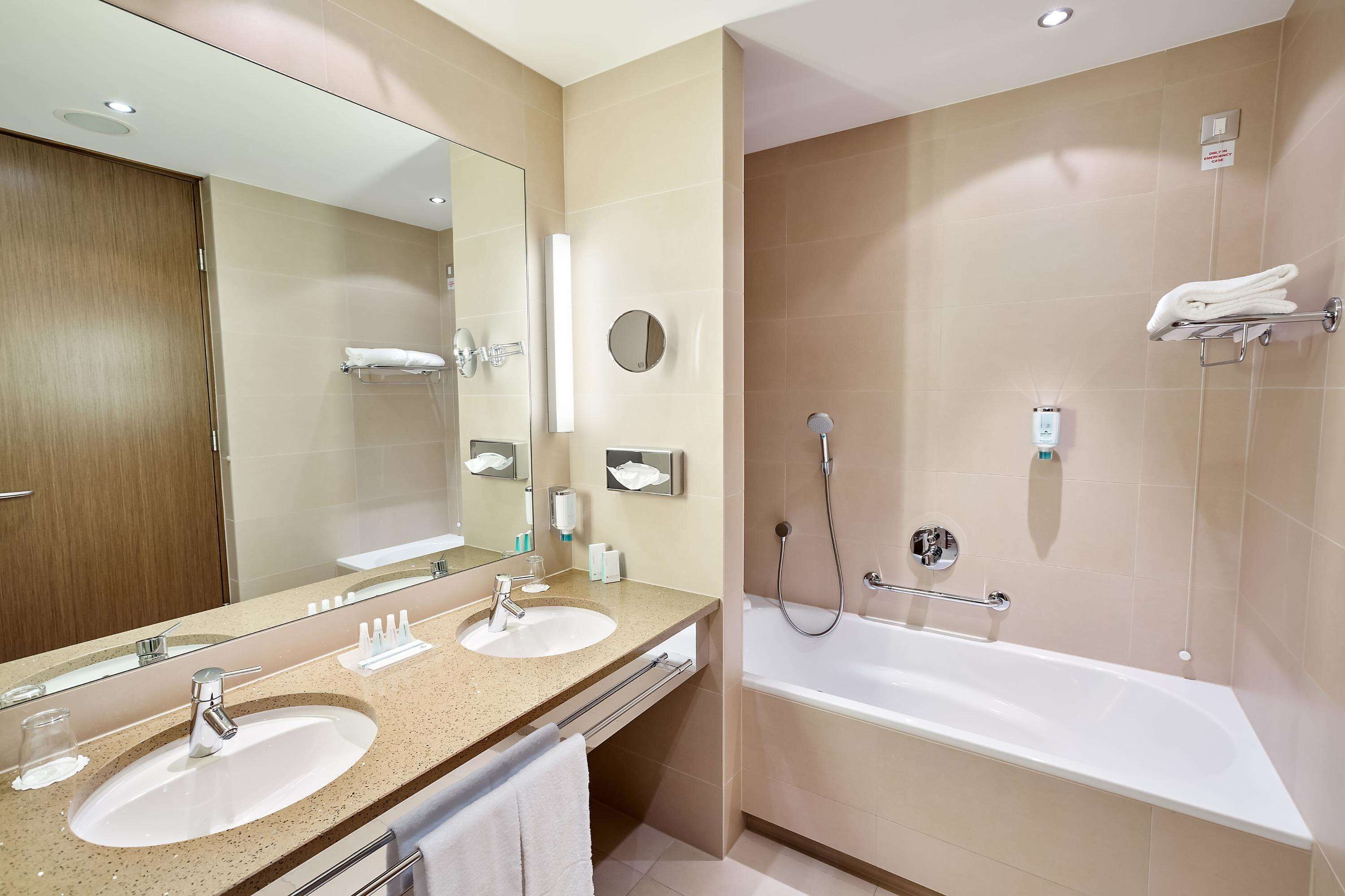 Ein modernes Badezimmer mit zwei Waschbecken, einem großen Spiegel und einer Badewanne.