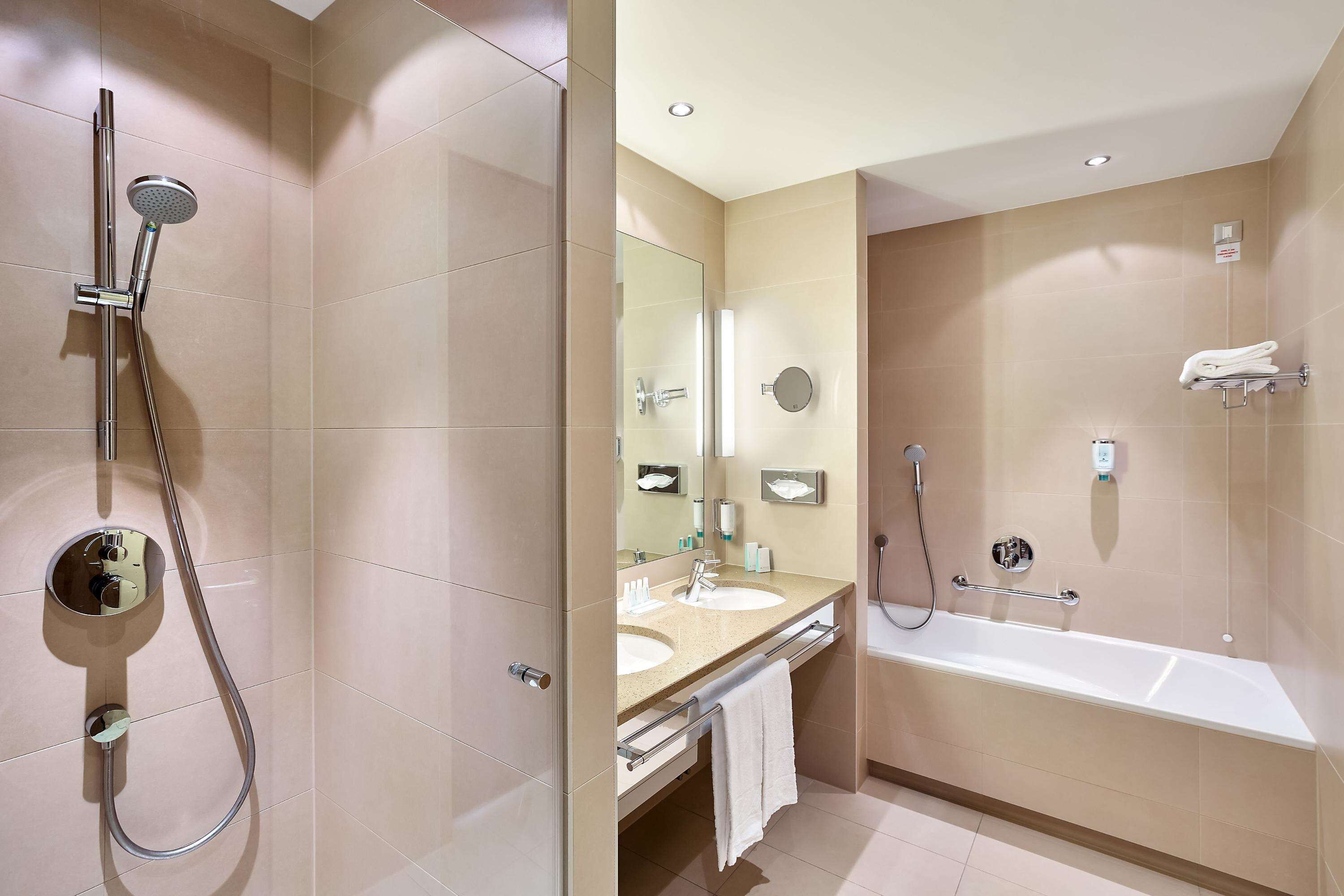 Ein modernes Badezimmer mit Dusche, Waschbecken, Spiegel und Badewanne.