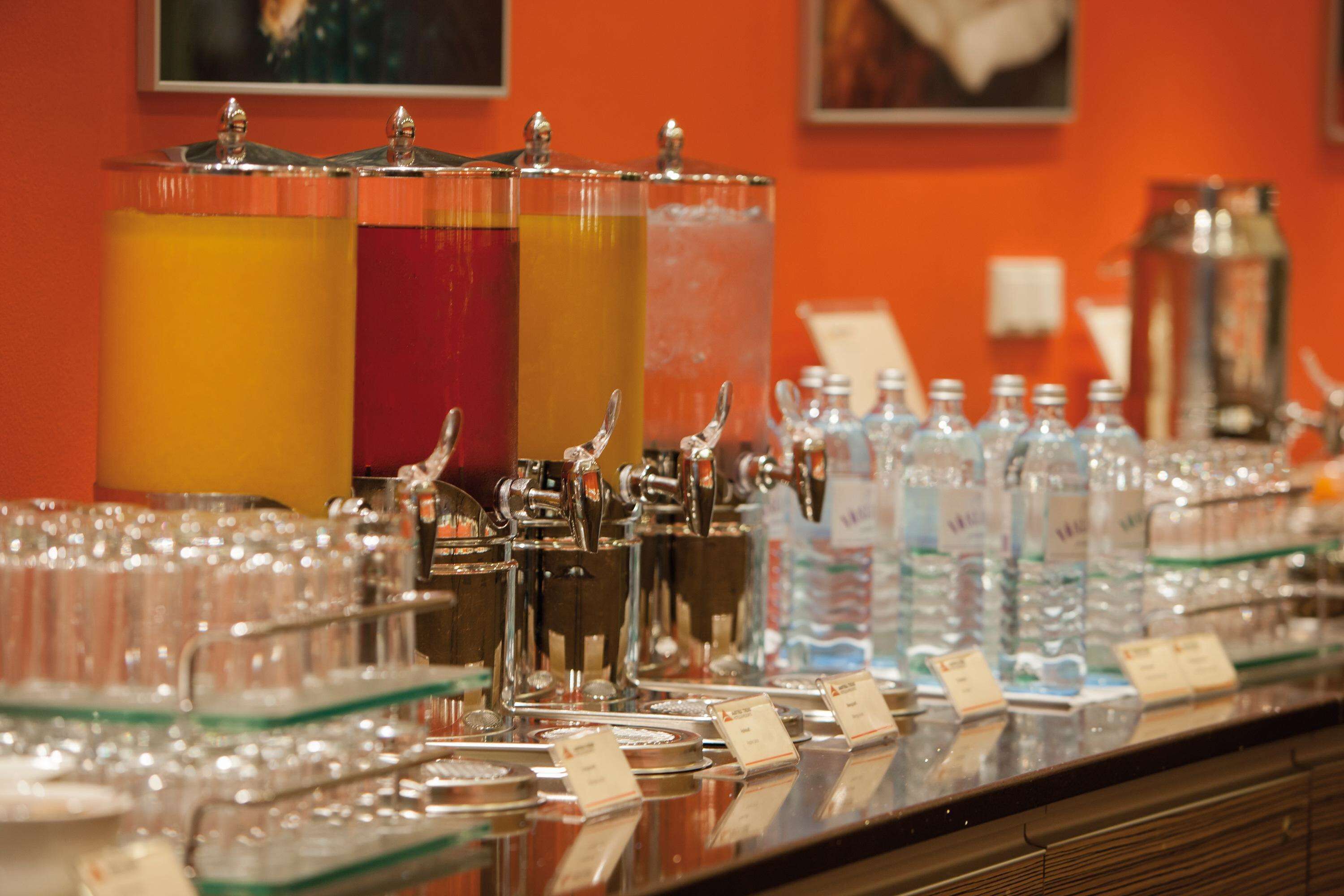 A beverage station with multiple dispensers and a variety of glassware.