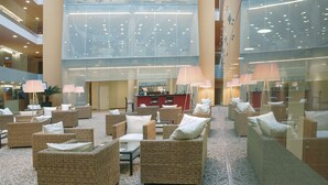 A spacious lobby with wicker furniture, a reception desk, and large windows.