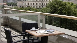 A balcony with a table, chairs, and a view of a large building with domes.