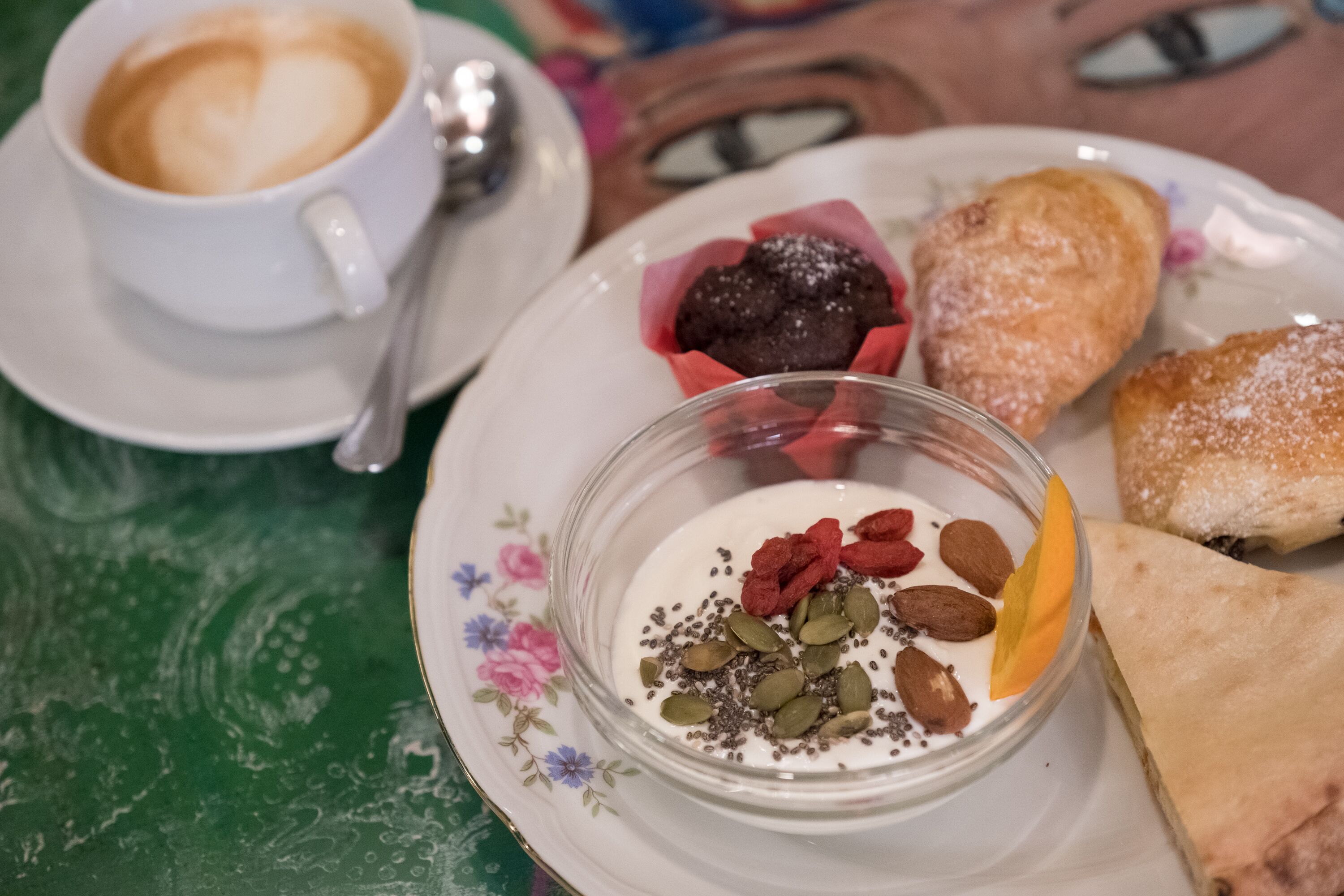 A plate with a dessert, a cup of coffee, and a pastry on a table.