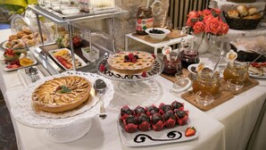 A buffet with various food items, including pastries, fruits, and beverages. - Charme Hotel Henry's House (Syracuse)