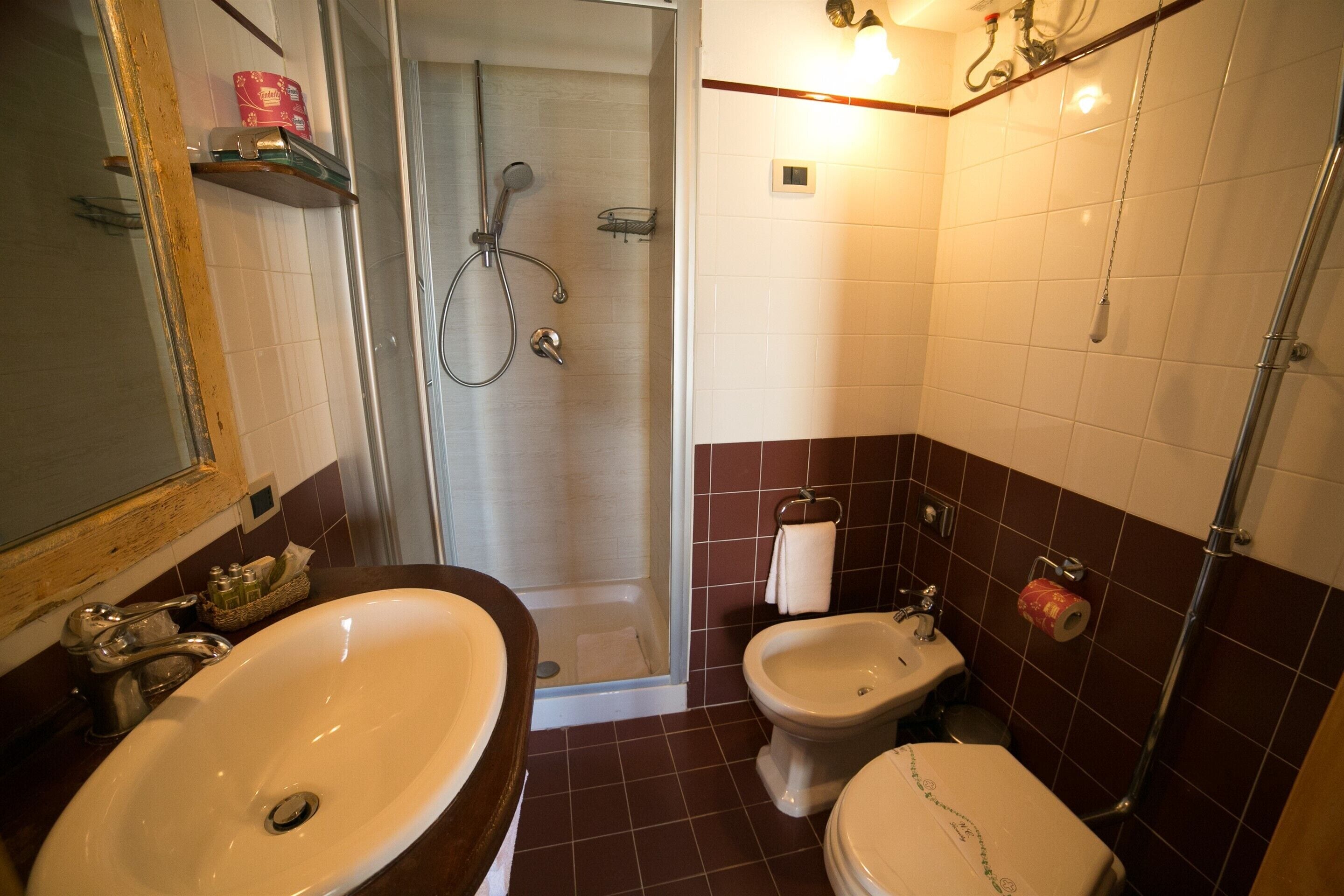 Ein Badezimmer mit einem großen Waschbecken, einem Bidet, einer Toilette und einer Duschkabine.