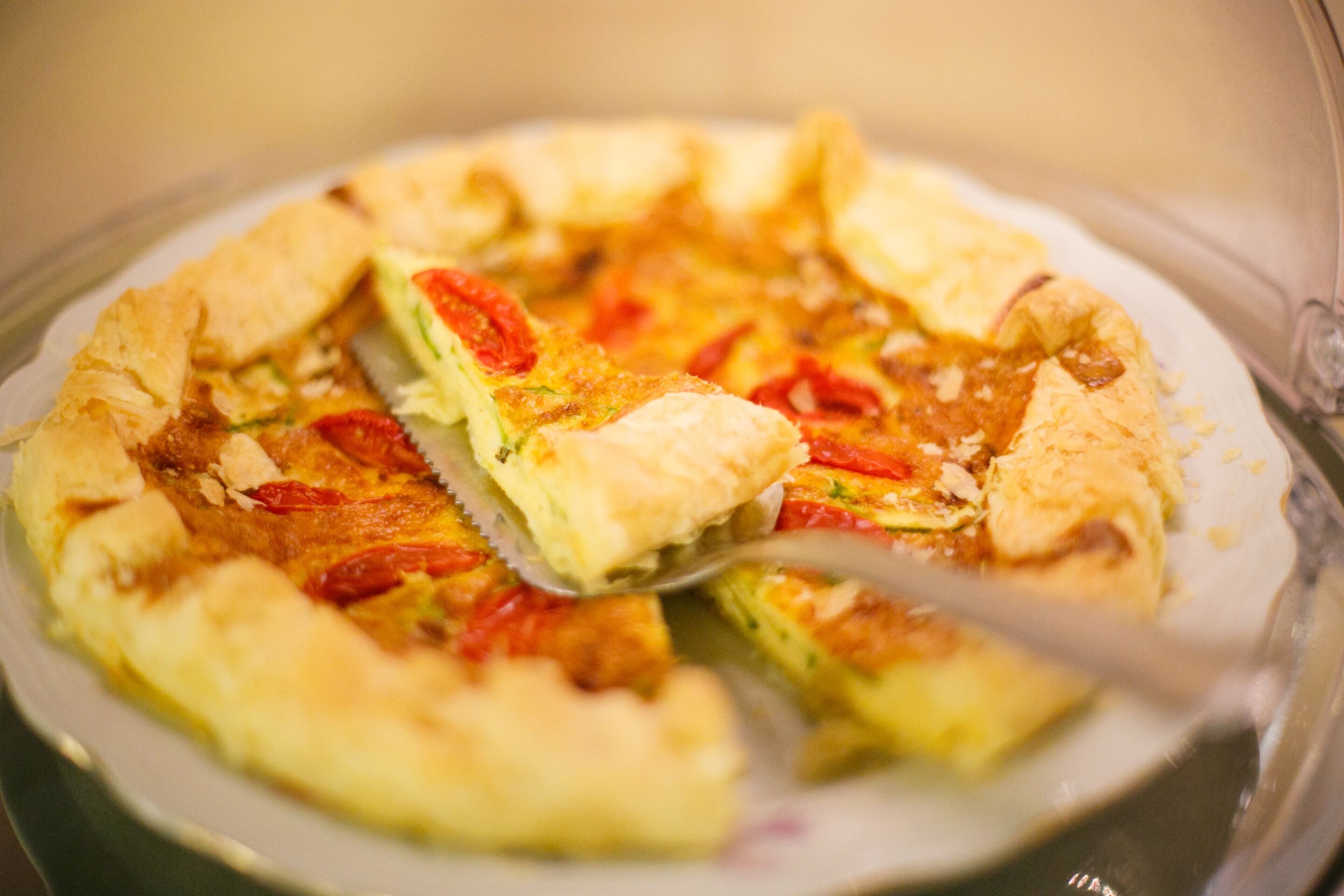 A pizza with a golden crust and toppings, served on a clear glass plate.