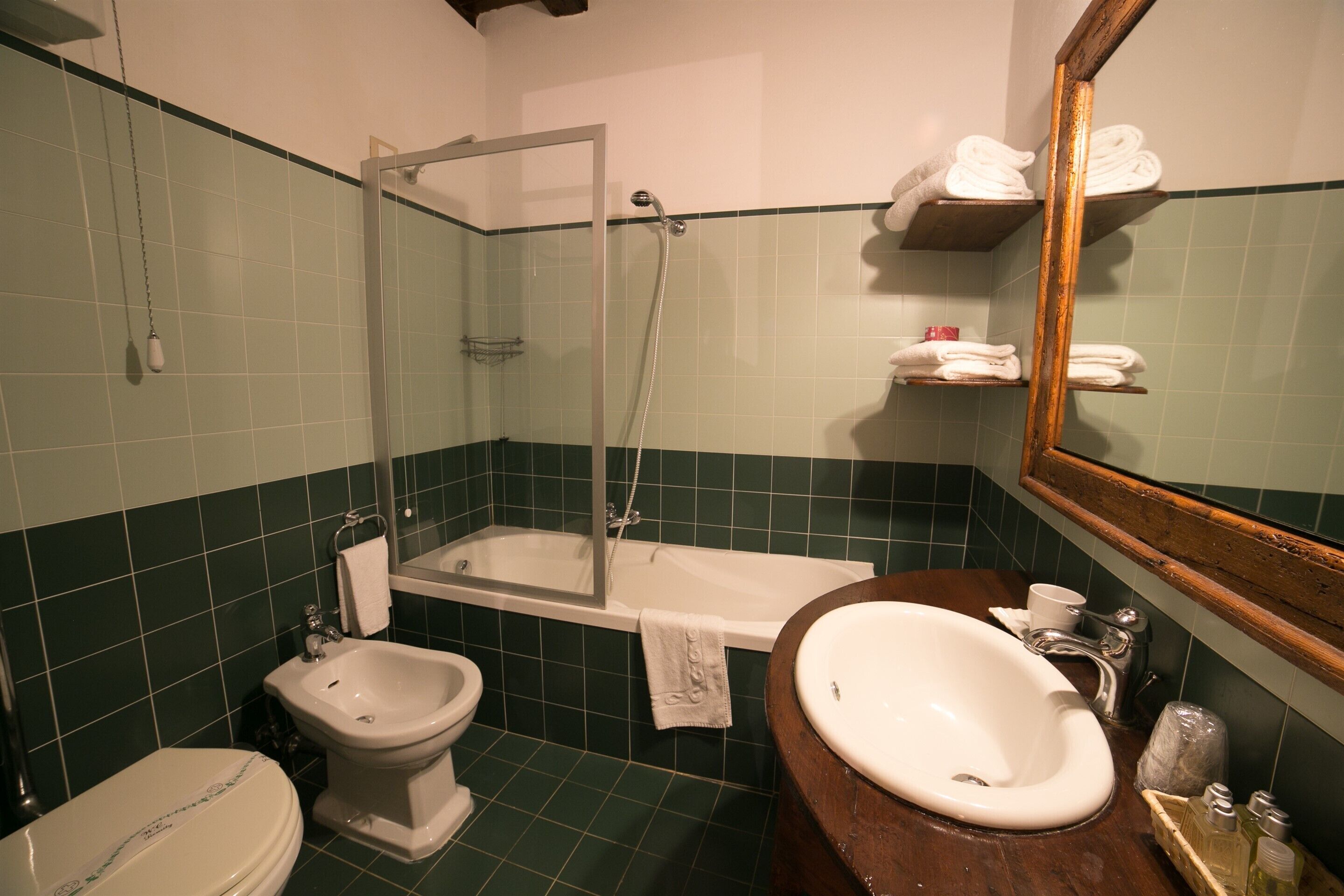 A bathroom with a bathtub, a bidet, a toilet, a sink, and a mirror.