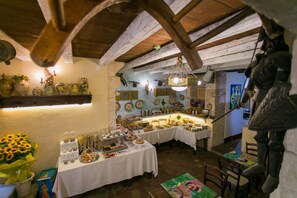 A rustic dining area with wooden beams, white tablecloths, and various dishes and decorations. - Charme Hotel Henry's House (Syracuse)