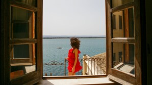 A view from an open window overlooking a body of water with a distant shoreline. - Charme Hotel Henry's House (Syracuse)