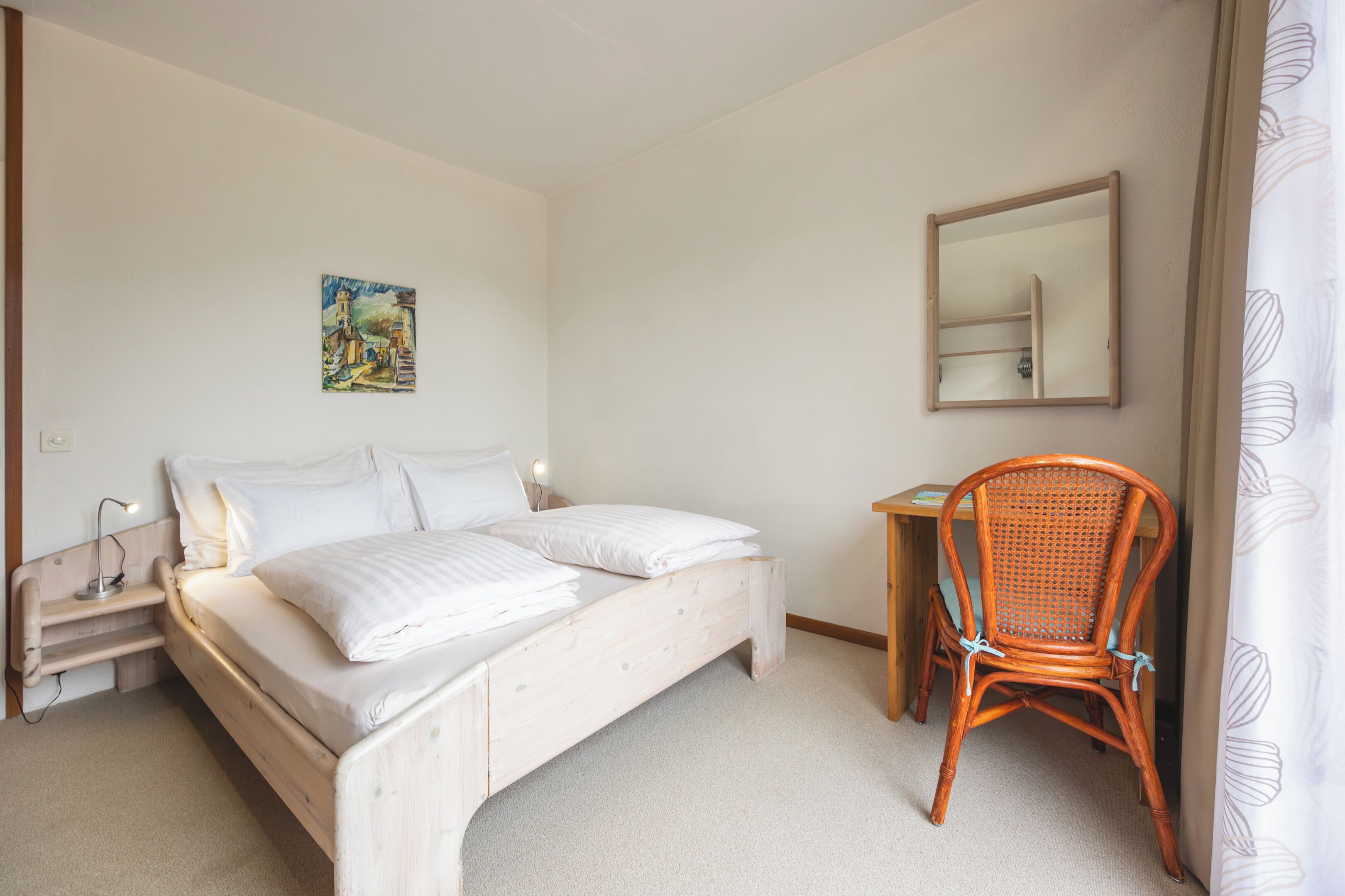 Une chambre à coucher avec un lit, une chaise, un bureau, une table de chevet, un tableau et un miroir.
