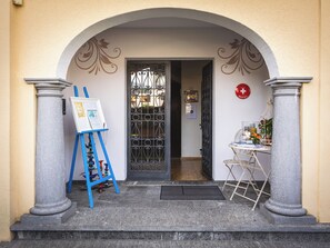 An entrance with a blue easel, a door with a metal gate, and a small table with a red sign.