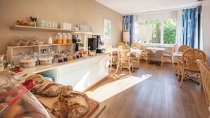 A breakfast buffet with various food items and a seating area with wicker chairs. - Villa Siesta, Park & Pool Living (Losone)