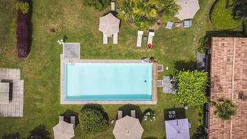 Una piscina al aire libre, sombrillas, sillones reclinables de piscina
