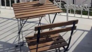 A balcony with a wooden table and bench, overlooking a beach with palm trees and a clear sky. - Hotel Sol Playa (Valencia)