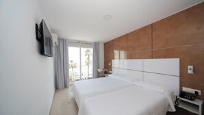 A hotel room with two beds, a TV mounted on the wall, a balcony with a view of palm trees, and a wooden accent wall. - Hotel Sol Playa (Valencia)