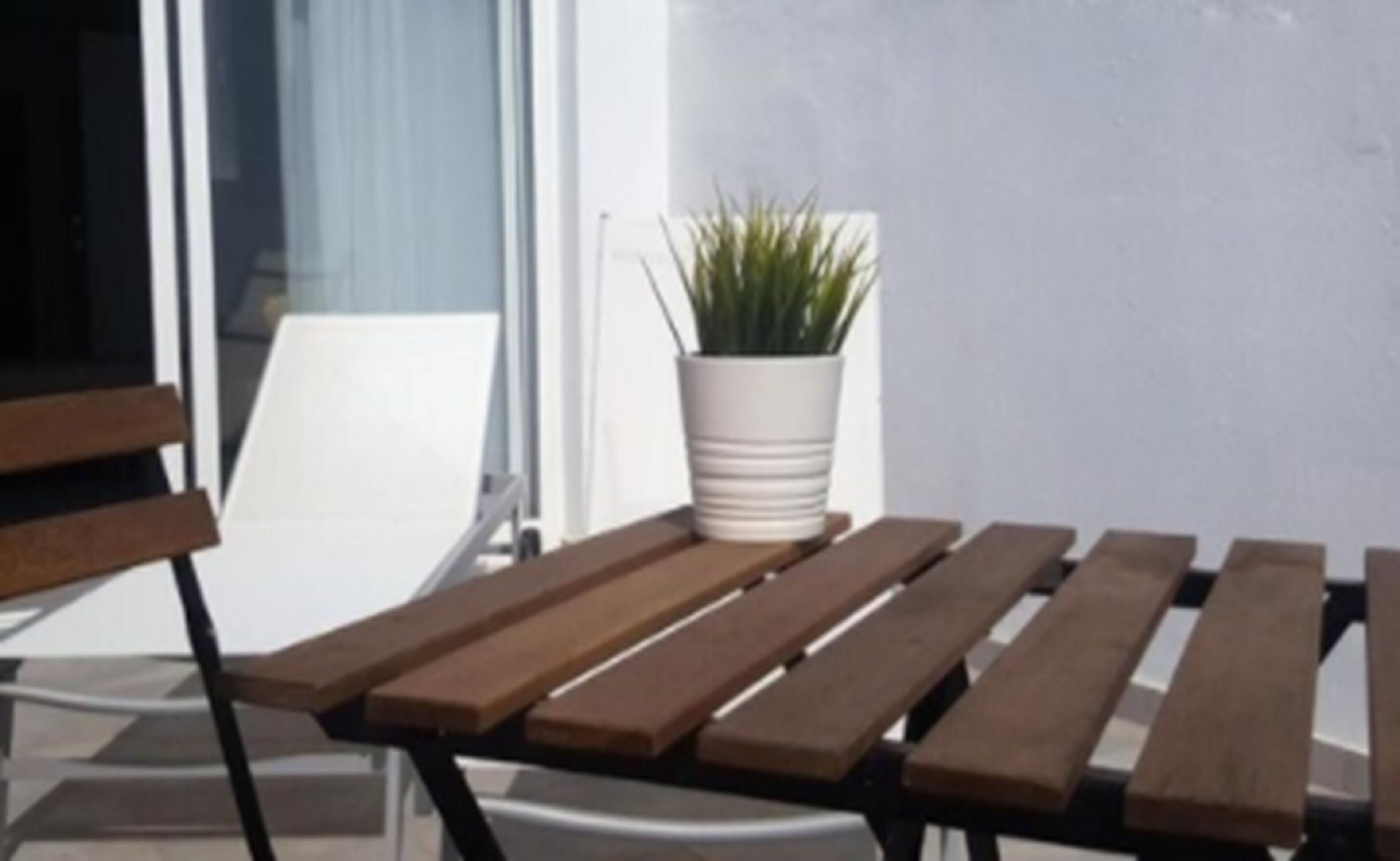 En træbænk med en plantekasse på en balkon.