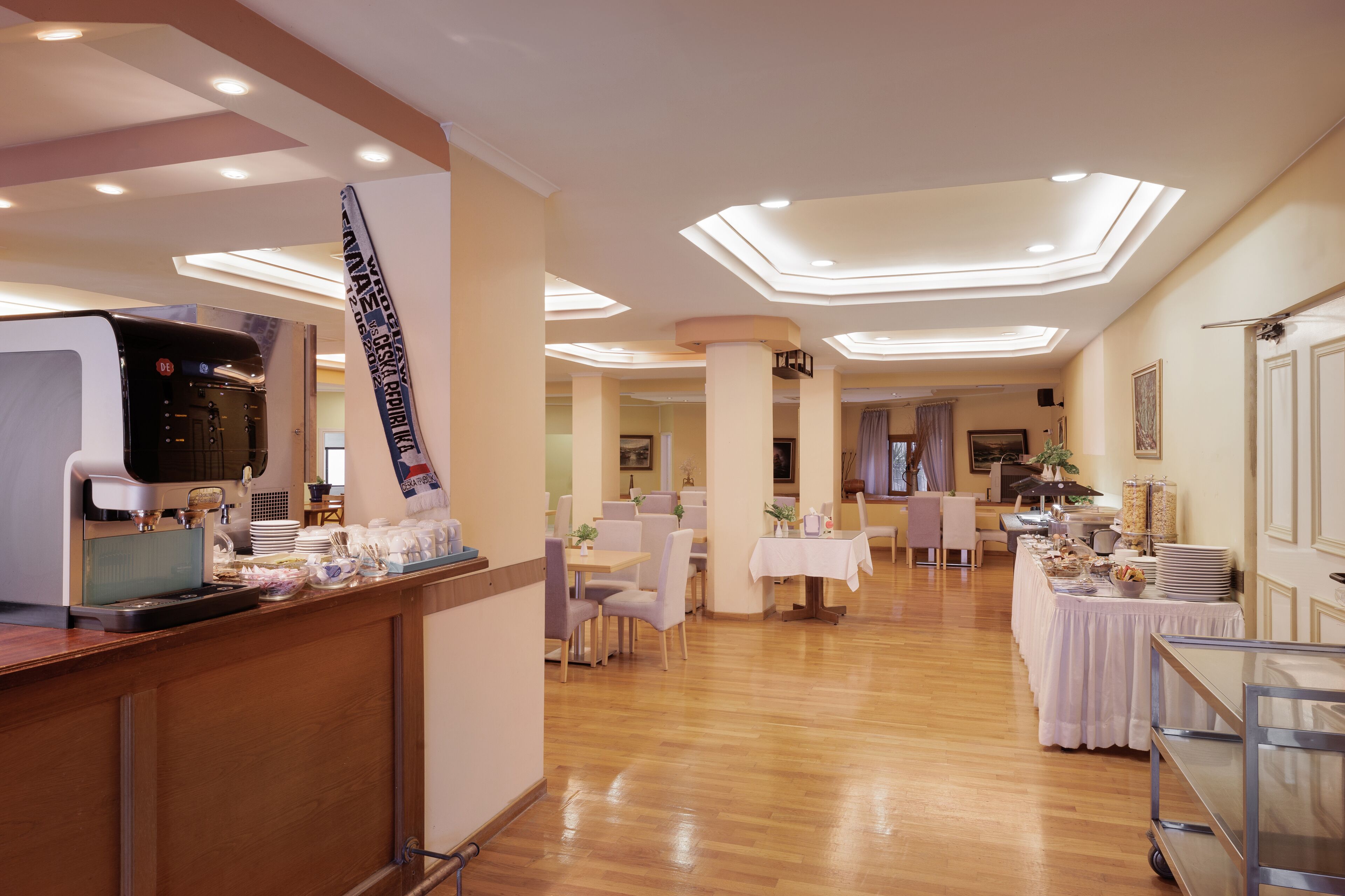 Un vestíbulo de hotel con recepción, zona de estar y una mesa de desayuno buffet.