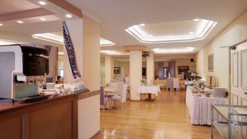 Un vestíbulo de hotel con recepción, zona de estar y una mesa de desayuno buffet.