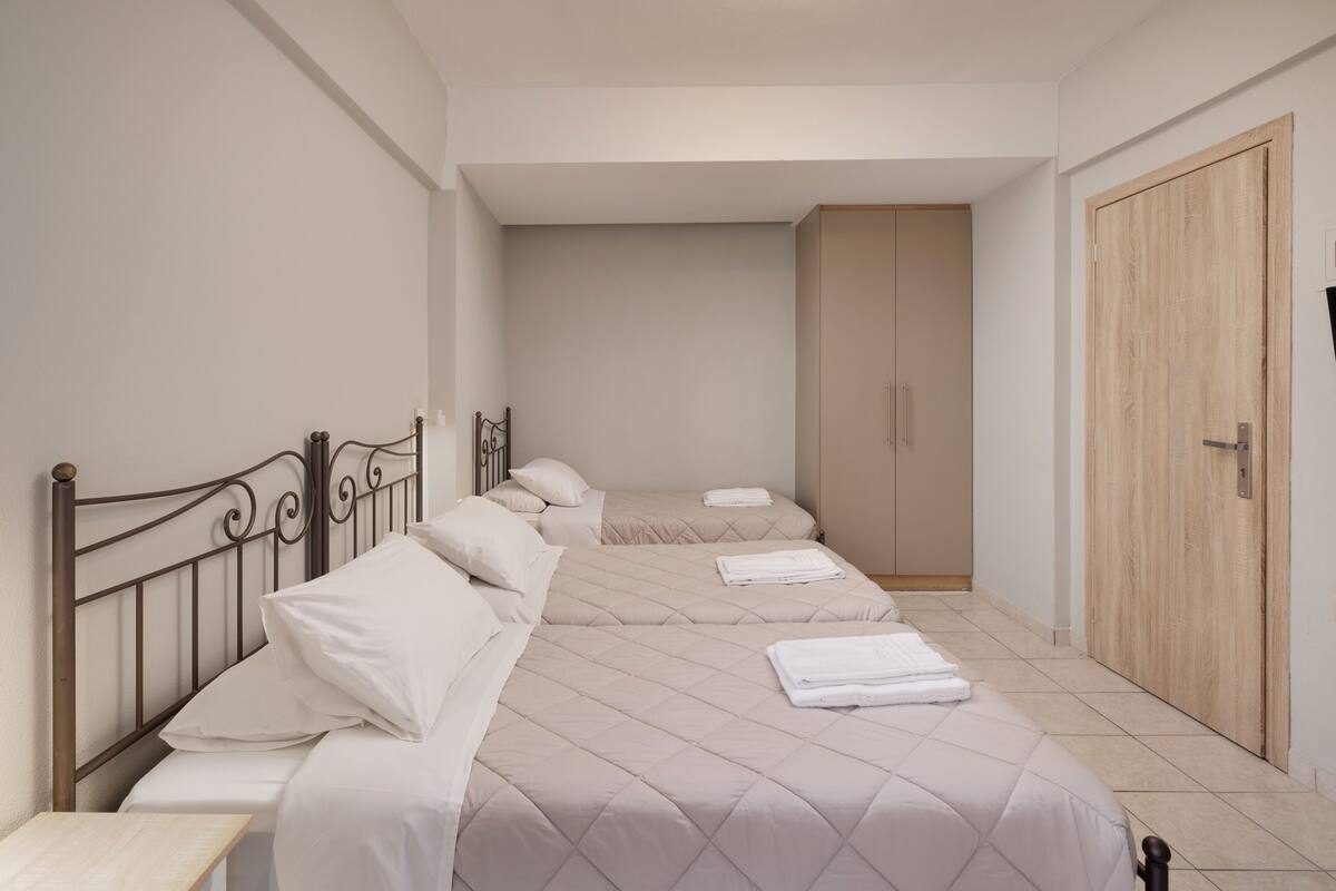 Un dormitorio con dos camas, un armario y una mesita de noche.