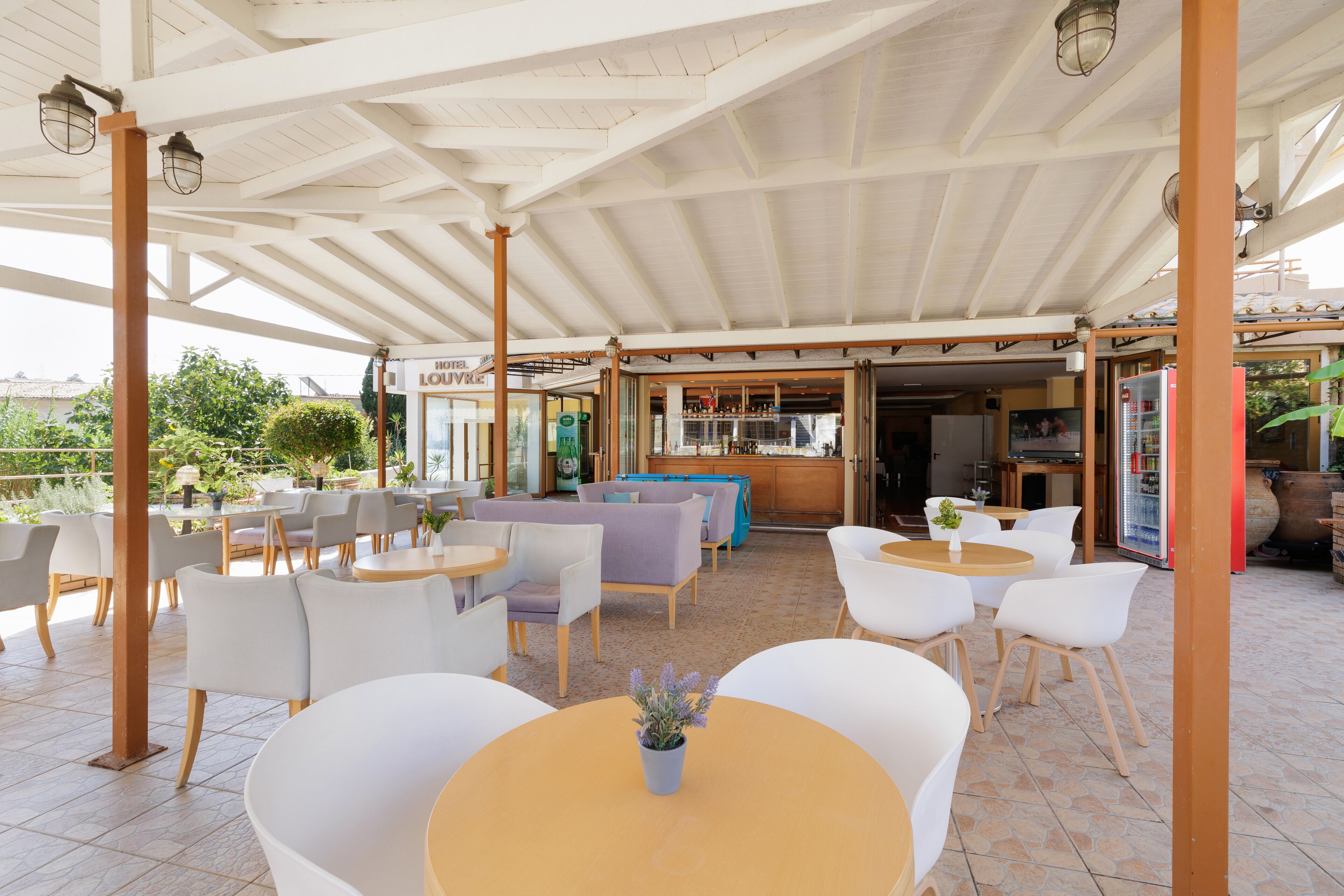 Un espacio de estar al aire libre techado, con mesas y sillas, una zona de bar y vistas del paisaje circundante.