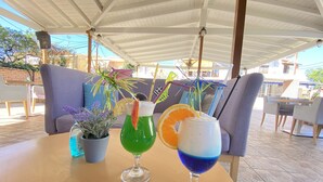 A table with three drinks, a potted plant, and a blue cushion. - Louvre Hotel (Corfu)