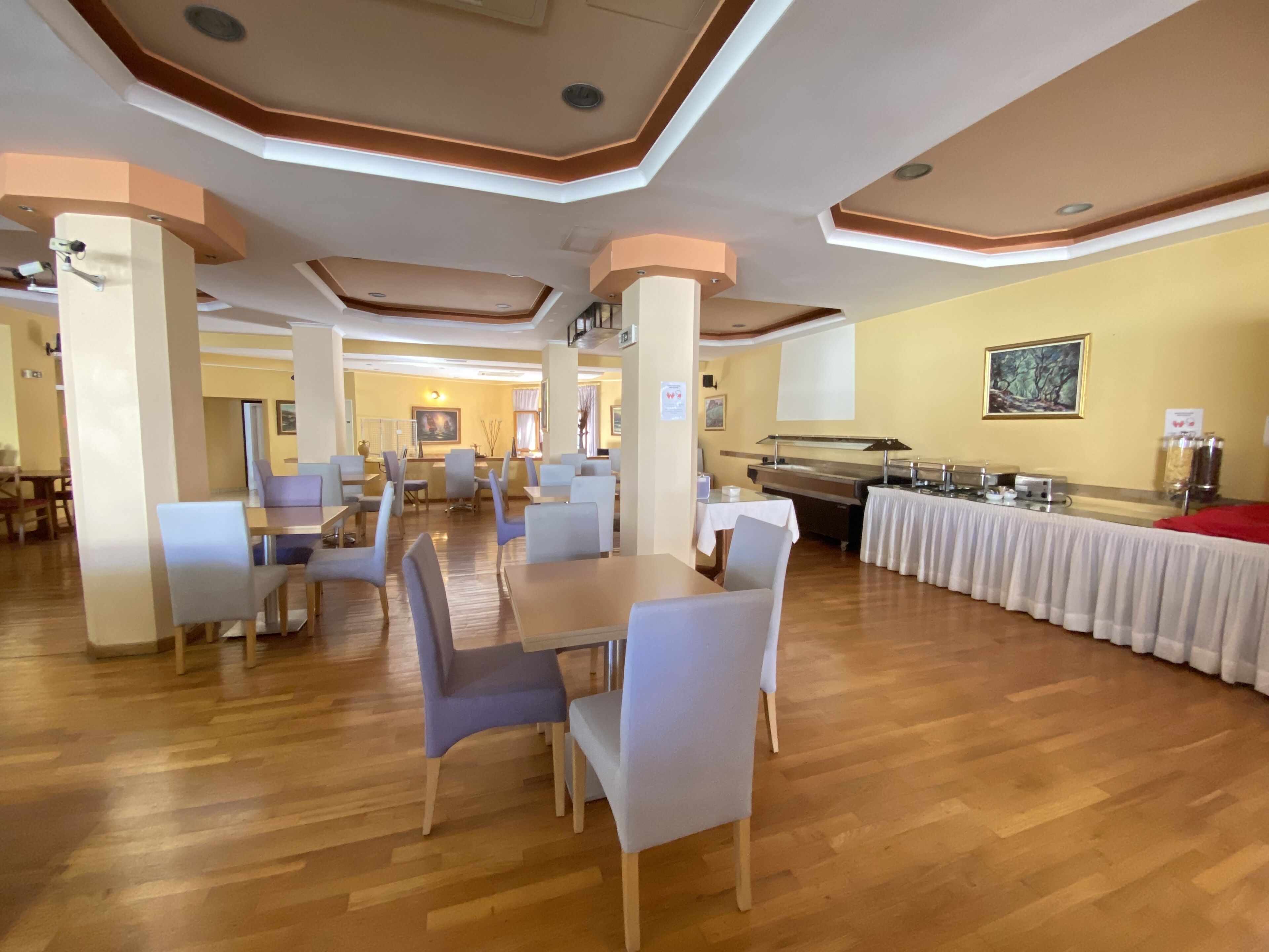 A spacious dining area with high ceilings, wooden flooring, and modern furniture.