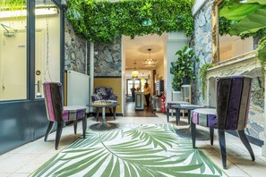 A lobby with a green leafy ceiling, patterned walls, and a central seating area with two chairs and a small table. - Young & Happy Latin Quarter by Hiphophostels (Paris)