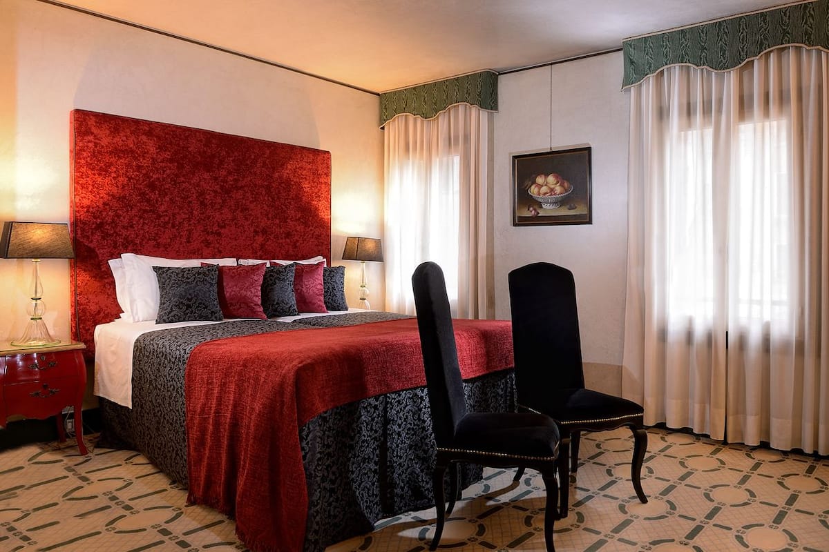 Une chambre d’hôtel avec un grand lit, une chaise, une table de chevet et une lampe.