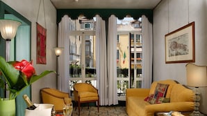 A cozy room with a yellow sofa, a green plant, and a table with a bottle of champagne. - Palazzo del Giglio (Venice)