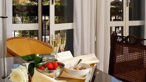 A dining area with a table set for two, featuring a bowl of strawberries, a white rose, and a glass of champagne. - Palazzo del Giglio (Venice)