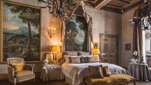 A bedroom with a four-poster bed, ornate chandeliers, and large landscape paintings on the walls. - Residenza Napoleone III (Rome)