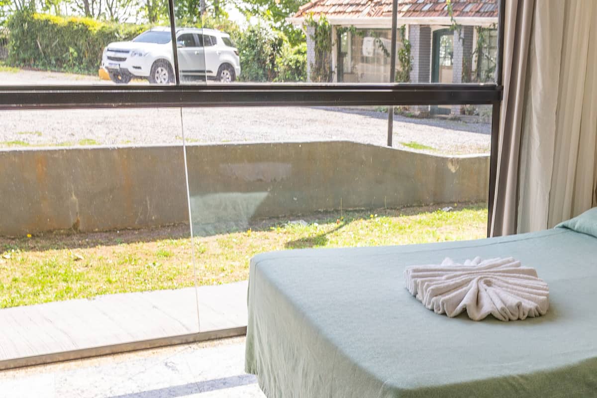 A hotel room with a bed, a window, and a view of a street.