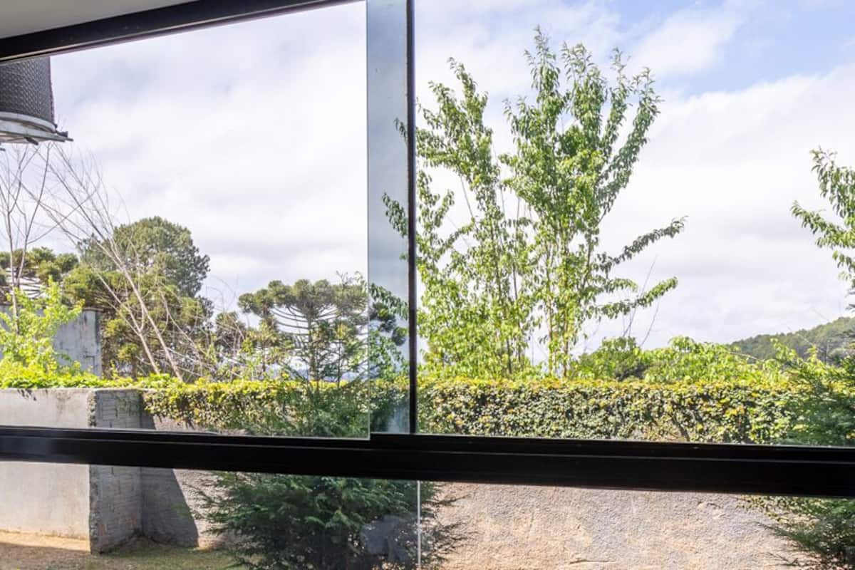 A room with a large window offering a view of a garden and trees.